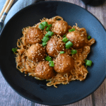 a bowl full of slow cooker meatballs and ramen with chopsticks