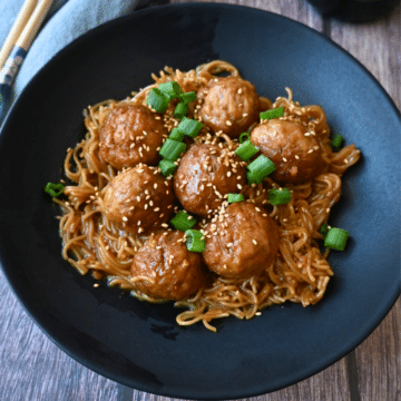 a bowl full of slow cooker meatballs and ramen with chopsticks