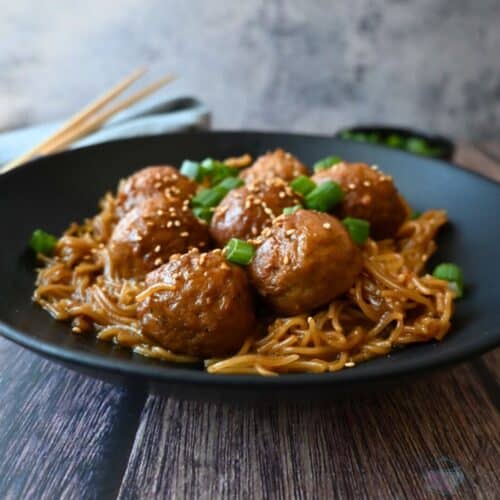 a bowl full of slow cooker meatballs and ramen with chopsticks