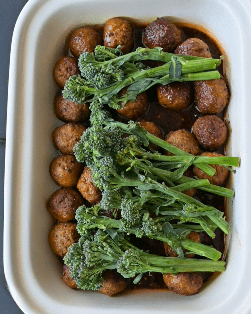 Broccolini in a slow cooker on top of meatballs