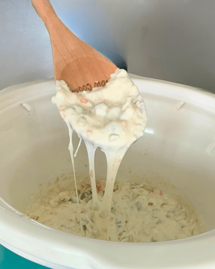 dirty martini dip on a spoon over a crockpot full of the same