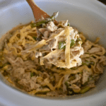 chicken and pasta with ceasar sauce on a spoon over a slow cooker full of the same