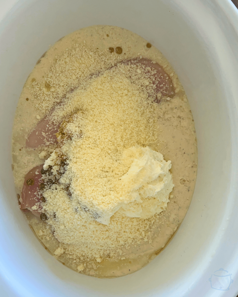 raw chicken and sauce ingredients in a crockpot