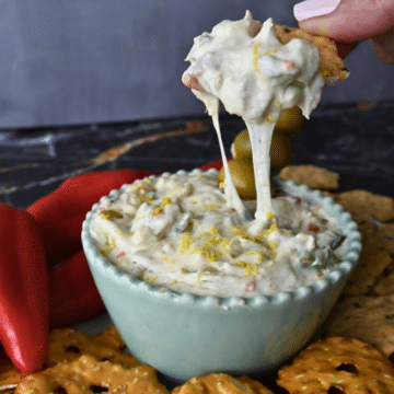 slow cooker dirty martini dip on a cracker over a bowl of the same