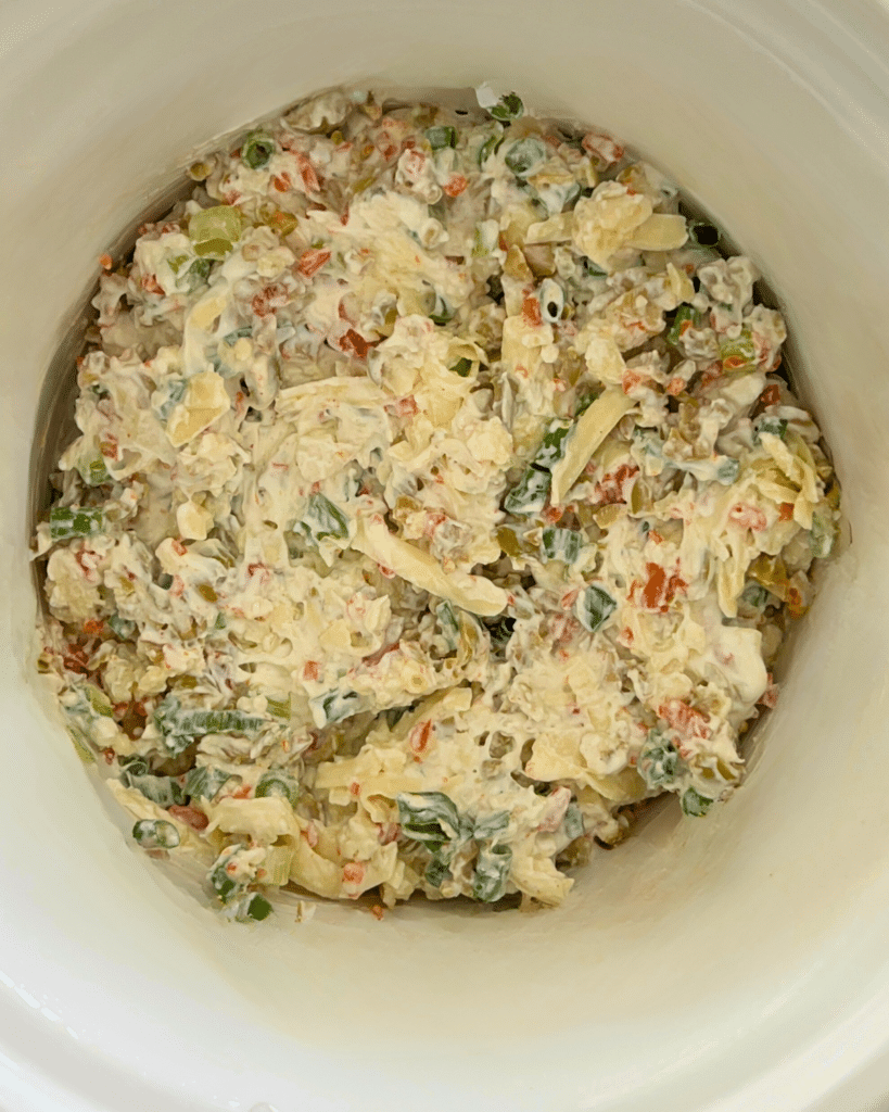 dirty martini dip ingredients in slow cooker before cooking mixed together 