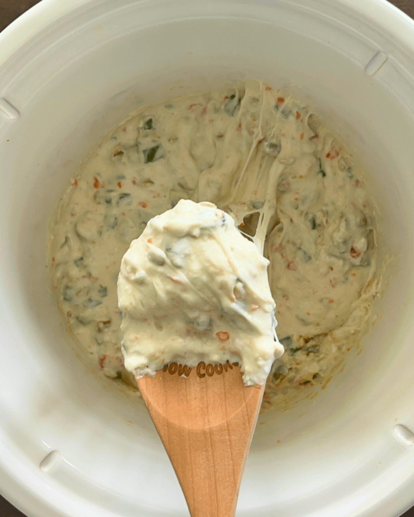 dirty martini dip on a spoon over a crockpot full of the same