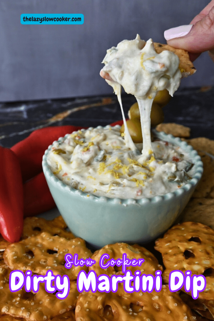 Dirty martini slow cooker dip in a bowl in the middle of pretzels crackers and peppers