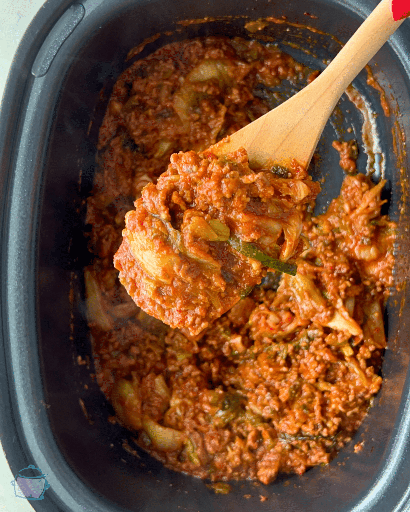kimchi sloppy Joe on a wooden spoon held over a slow cooker full of the same