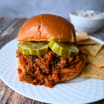 slow cooker kimchi sloppy joe on a brioche roll with a side of chips