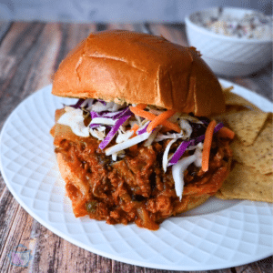 slow cooker kimchi sloppy joe on a brioche roll with a side of chips