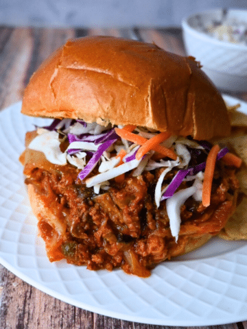 slow cooker kimchi sloppy joe on a brioche roll with a side of chips