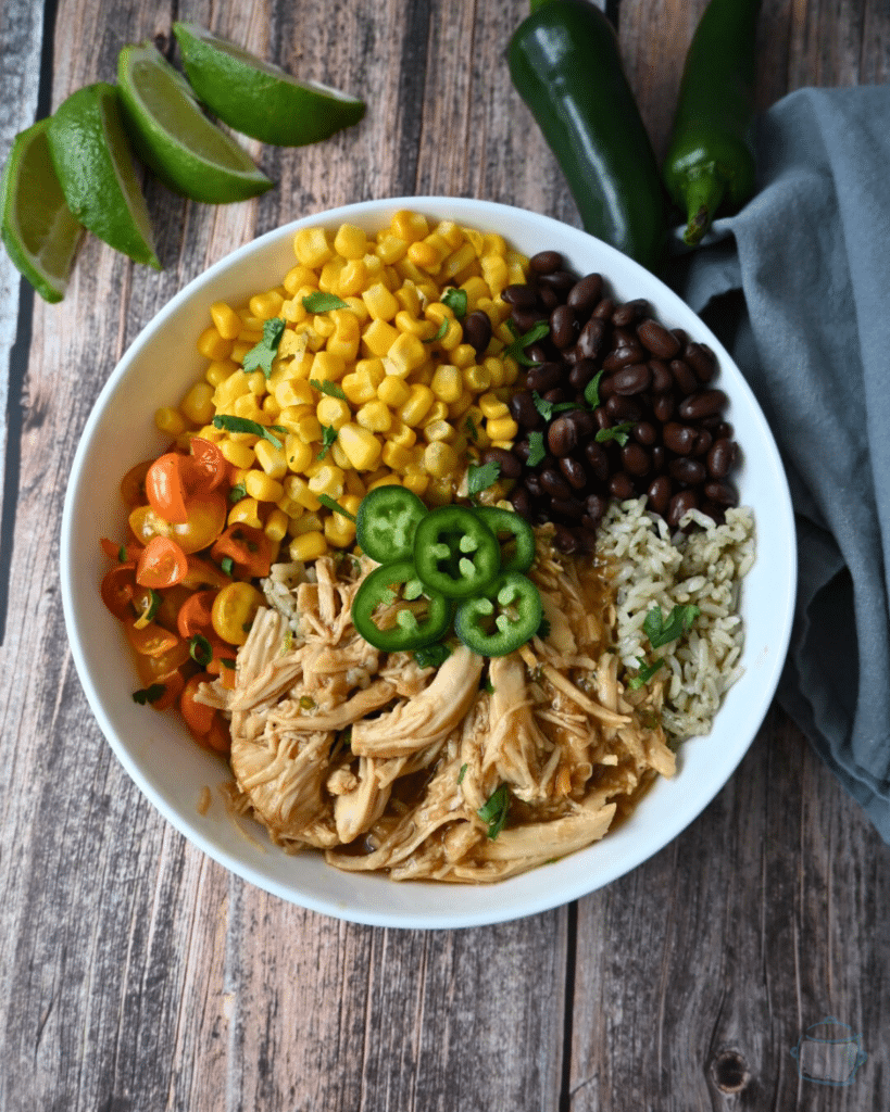 a bowl with maple lime chicken, rice, beans, corn and tomatoes