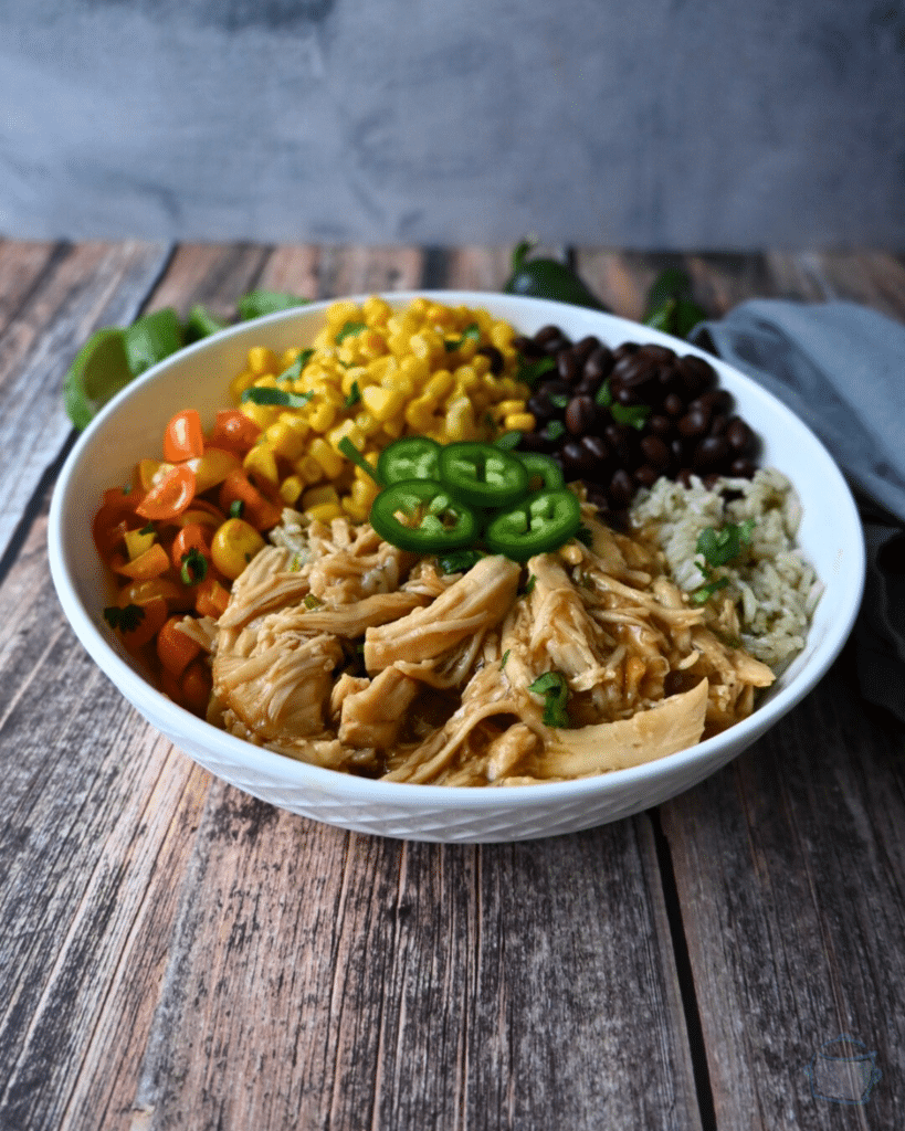 a bowl with maple lime chicken, rice, beans, corn and tomatoes