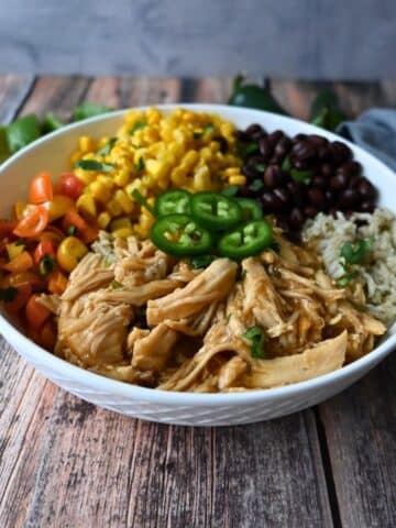 a bowl with maple lime chicken, rice, beans, corn and tomatoes