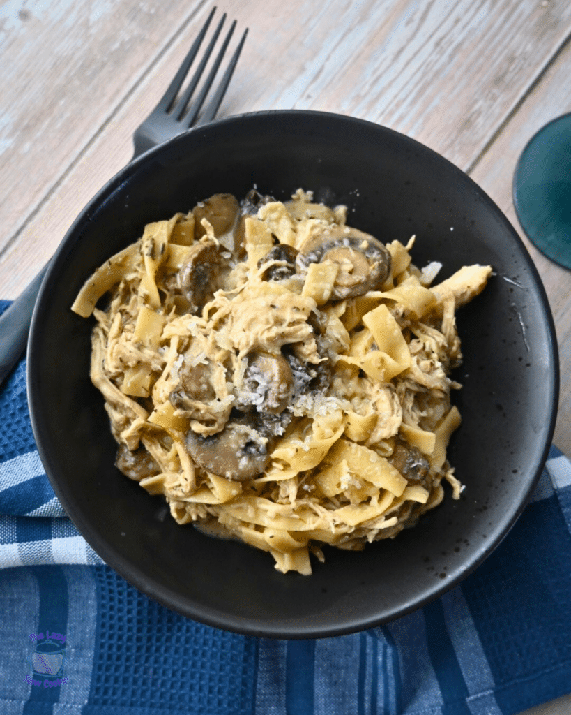 creamy slow cooker pasta with mushrooms and chicken in a black bowl