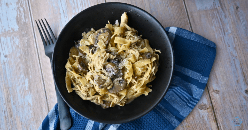 creamy slow cooker pasta with mushrooms and chicken in a black bowl