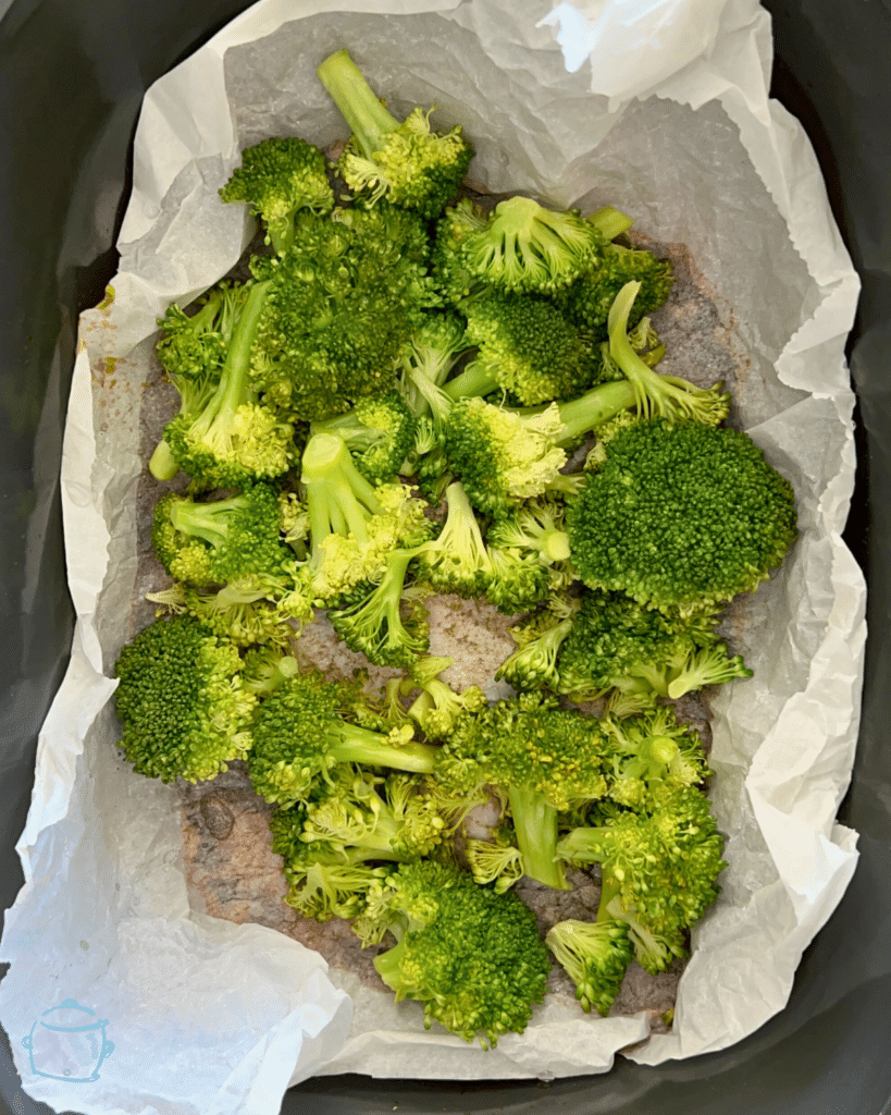 broccoli on parchment paper in a slow cooker