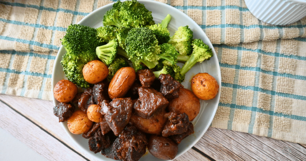 slow cooker bbq steak bites and potatoes on a plate with broccoli