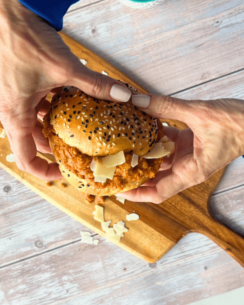 seeded bun filled with slow cooker ground chicken sloppy joes held by two hands