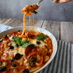 A bowl of pizza beans ready to be eaten with some on a fork