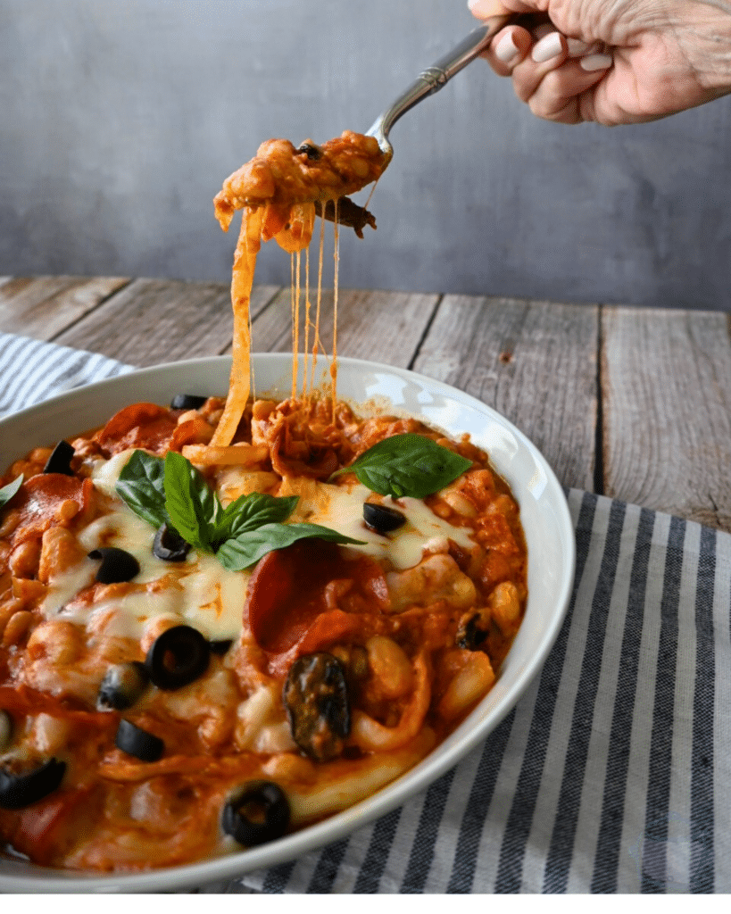 A bowl of pizza beans ready to be eaten with some on a fork