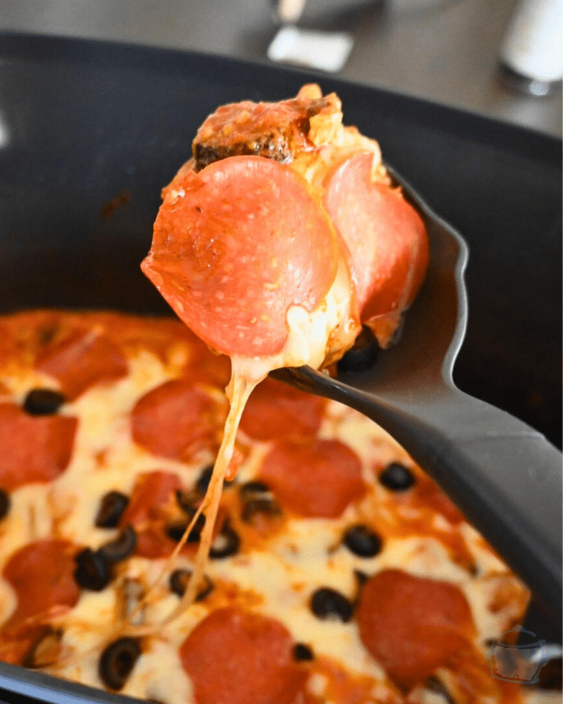 a spoon full of pizza beans held over a crockpot full of the same
