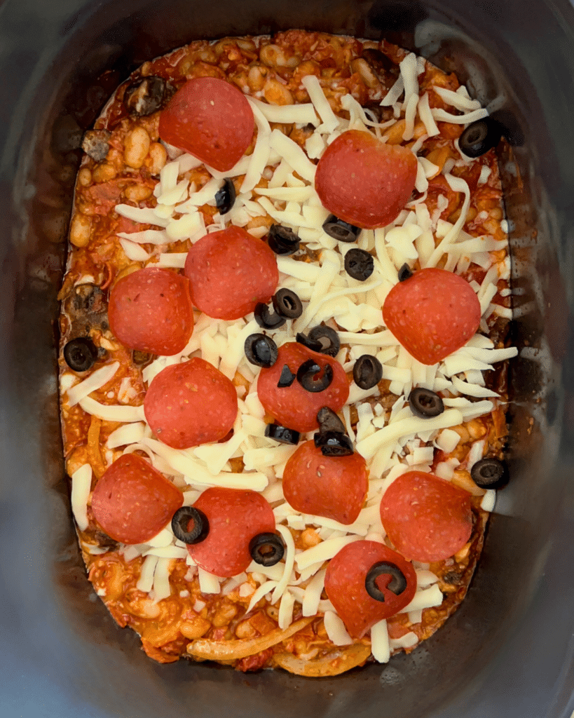 cooked pizza beans in a slow cooker with toppings added