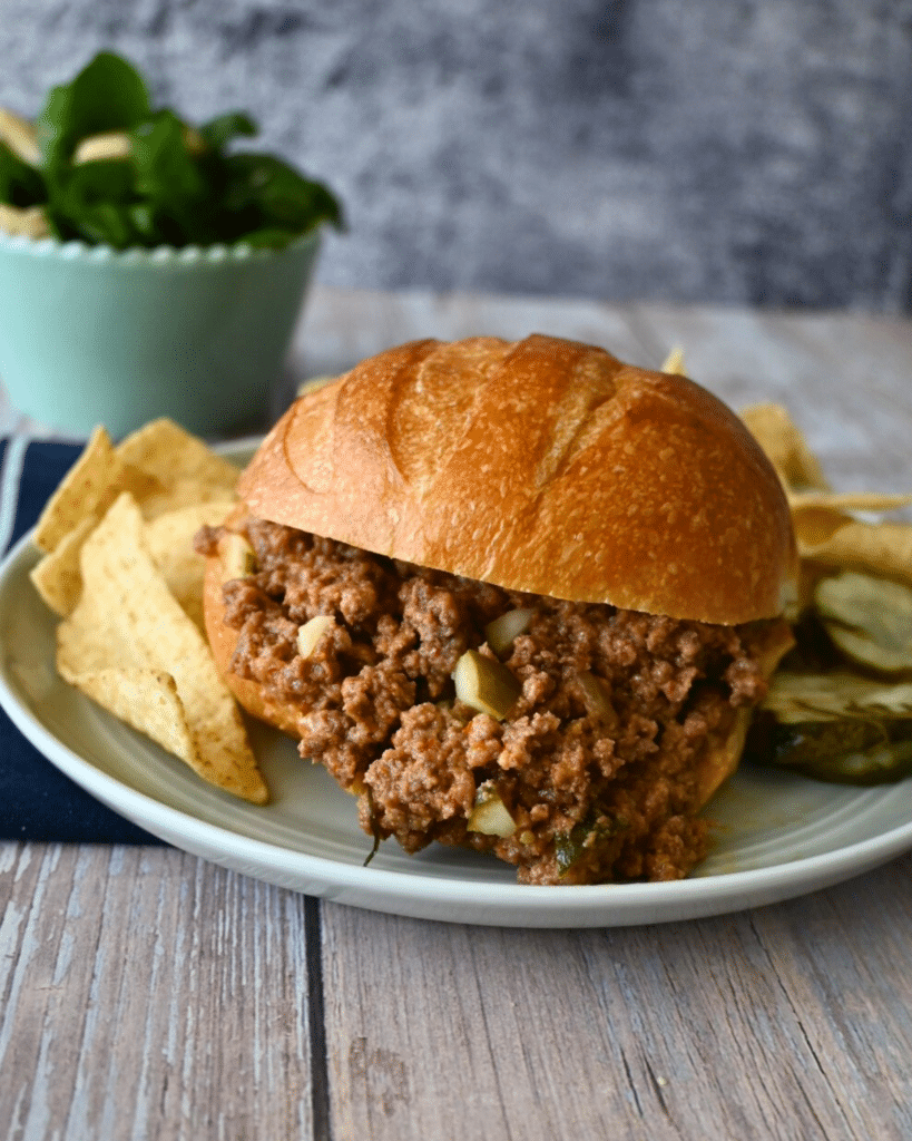 close up of a slow cooker dill pickle sloppy Joe sandwich with chips