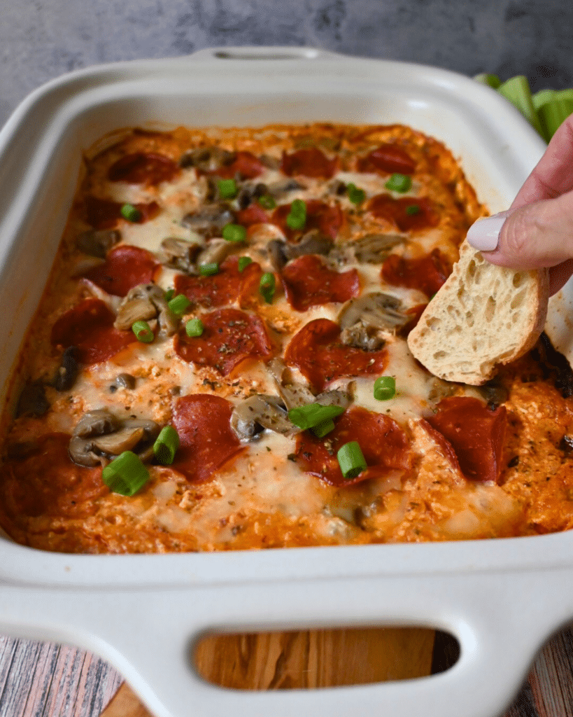 a small piece of toast dipping into crockpot pizza dip