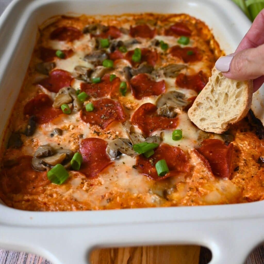 a small piece of toast dipping into crockpot pizza dip