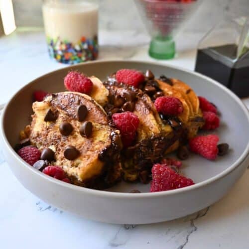 a bowl full of slow cooker chocolate chip pancake casserole topped with berries