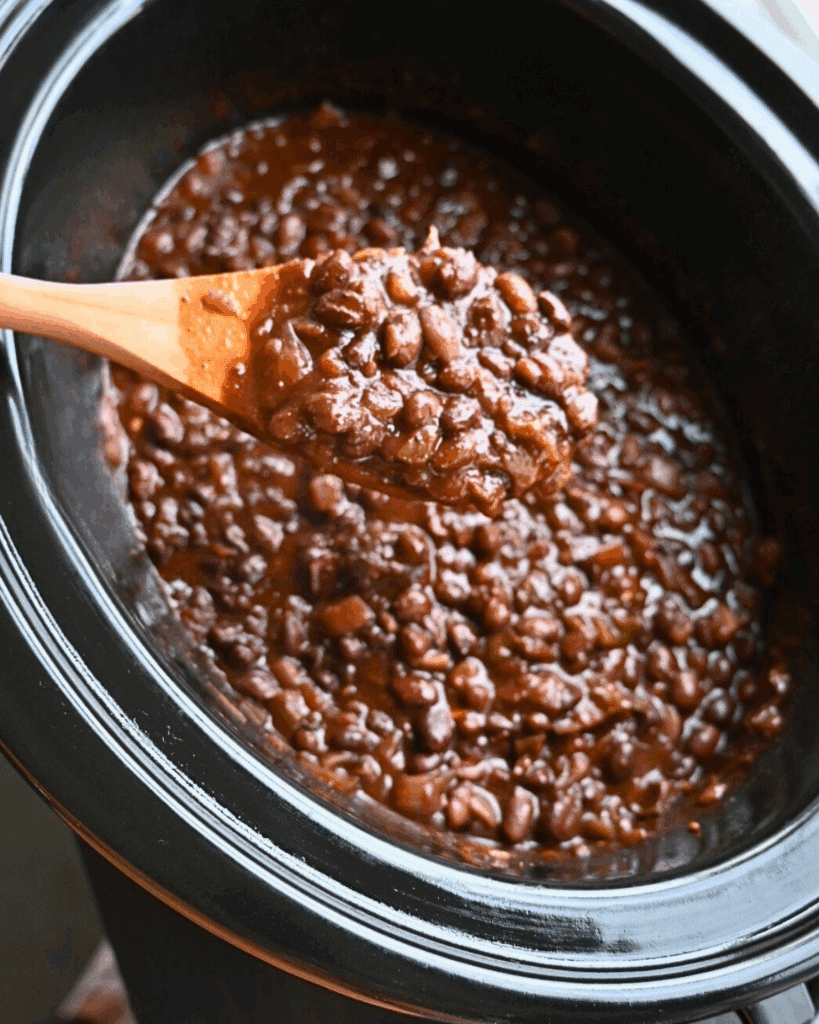 finished taco beans on a spoon over a slow cooker full of the same
