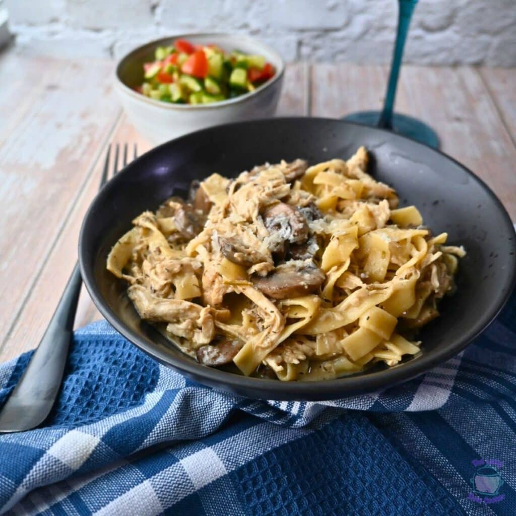 creamy slow cooker pasta with mushrooms and chicken in a black bowl