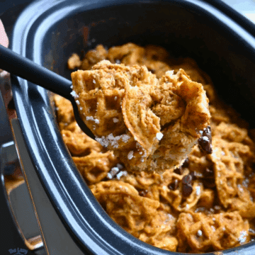 a slow cooker full of pumpkin waffle casserole ready to serve with some on a spoon