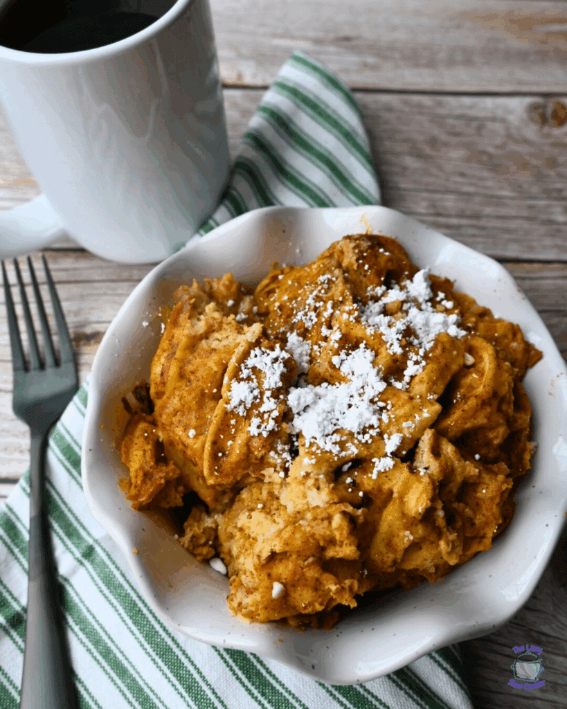 A bowl full of slow cooker pumpkin waffle casserole topped with powdered sugar