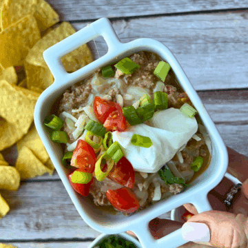 taco dip with cottage cheese and toppings in a single sized serving bowl surrounded by chips