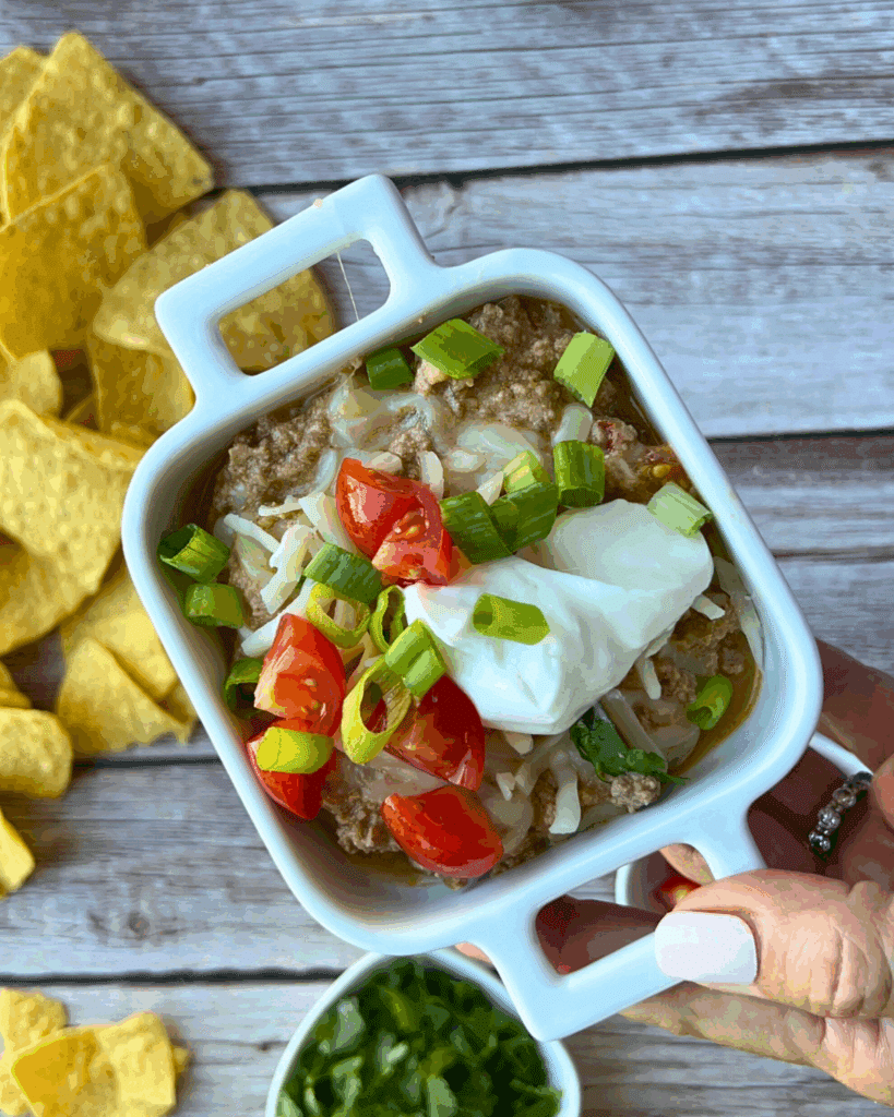 taco dip with cottage cheese and toppings in a single sized serving bowl surrounded by chips