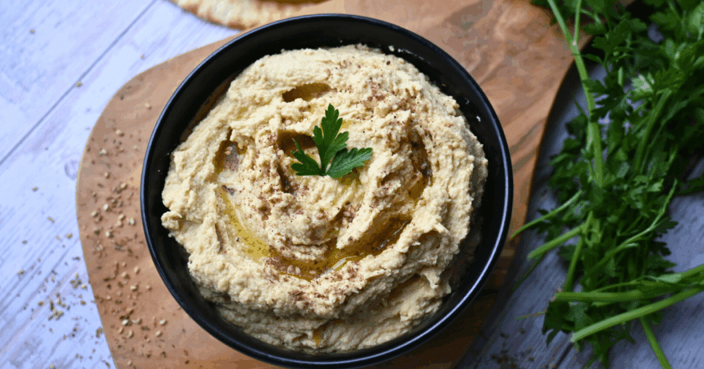 a bowl of homemade hummus on a wooden serving board