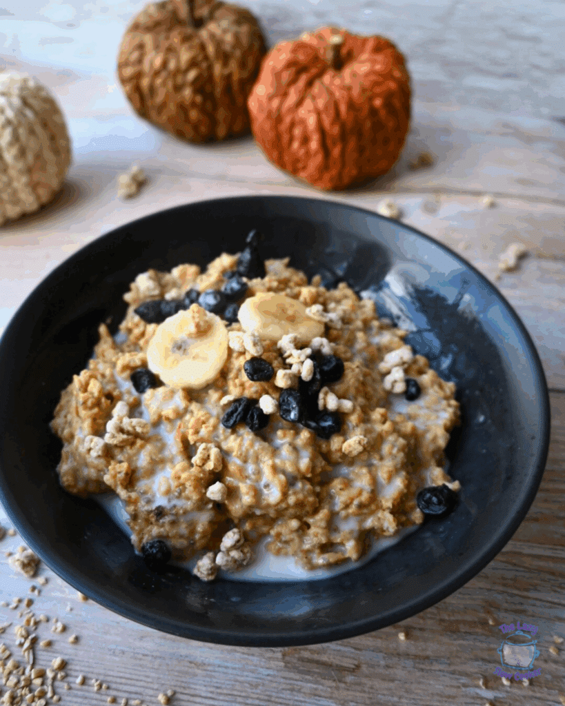 a black bowl filled with pumpkin pie overnight slow cooker oats topped with blueberries and bananas