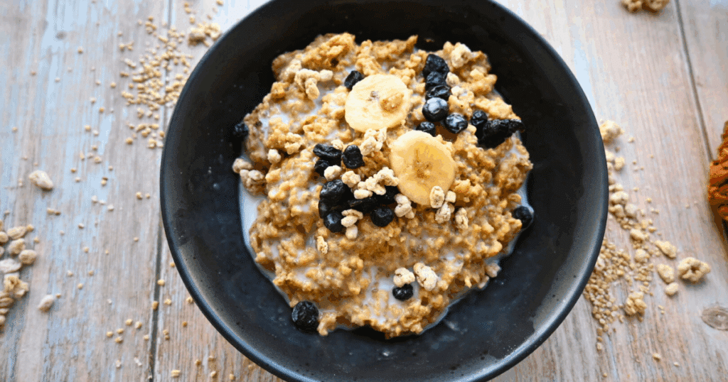 a black bowl filled with pumpkin pie overnight slow cooker oats topped with blueberries and bananas