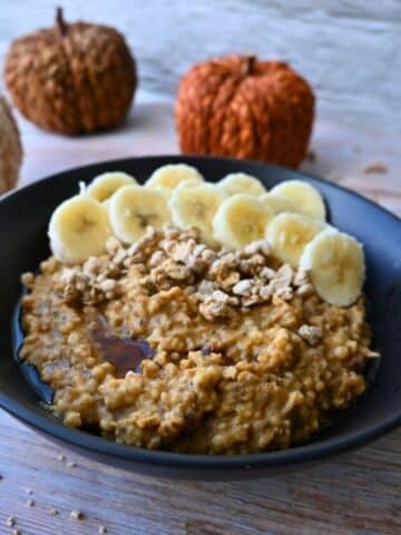 pumpkin oatmeal in a bowl topped with granola and bananas