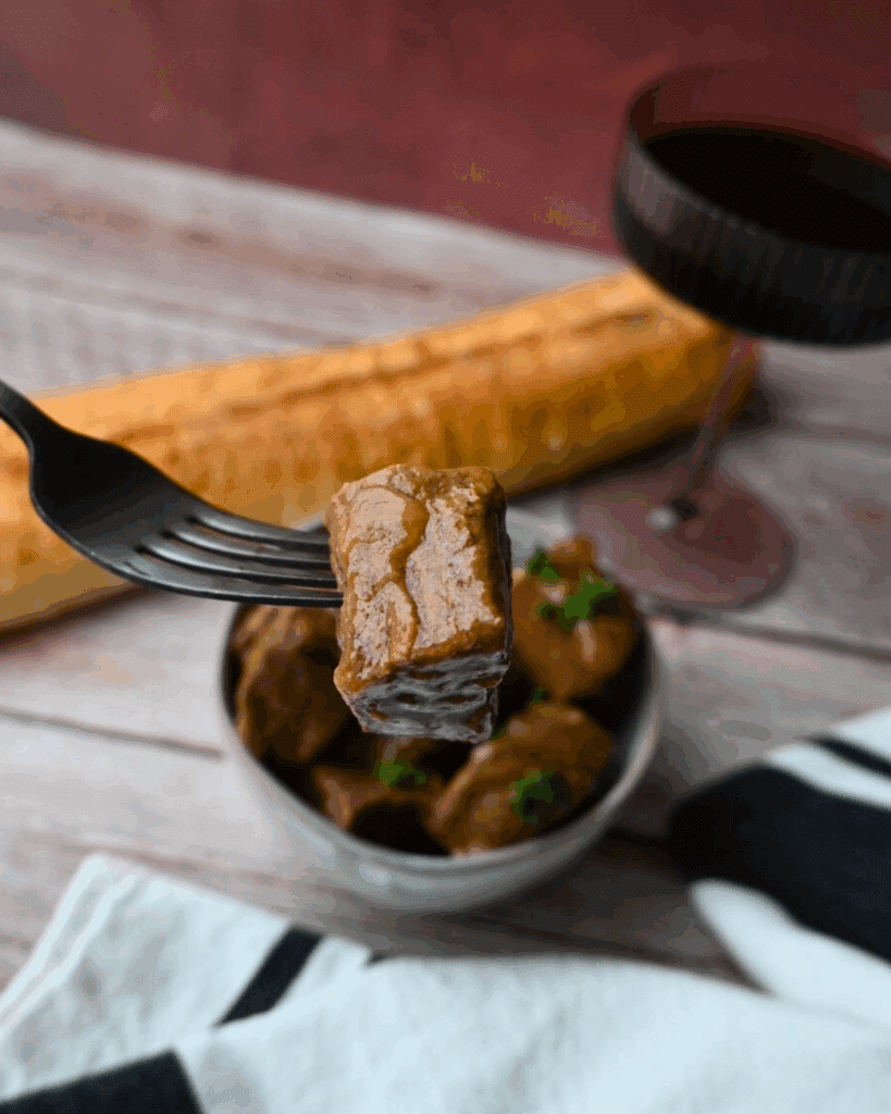 a single bite of beef on a fork over a bowl full of the same
