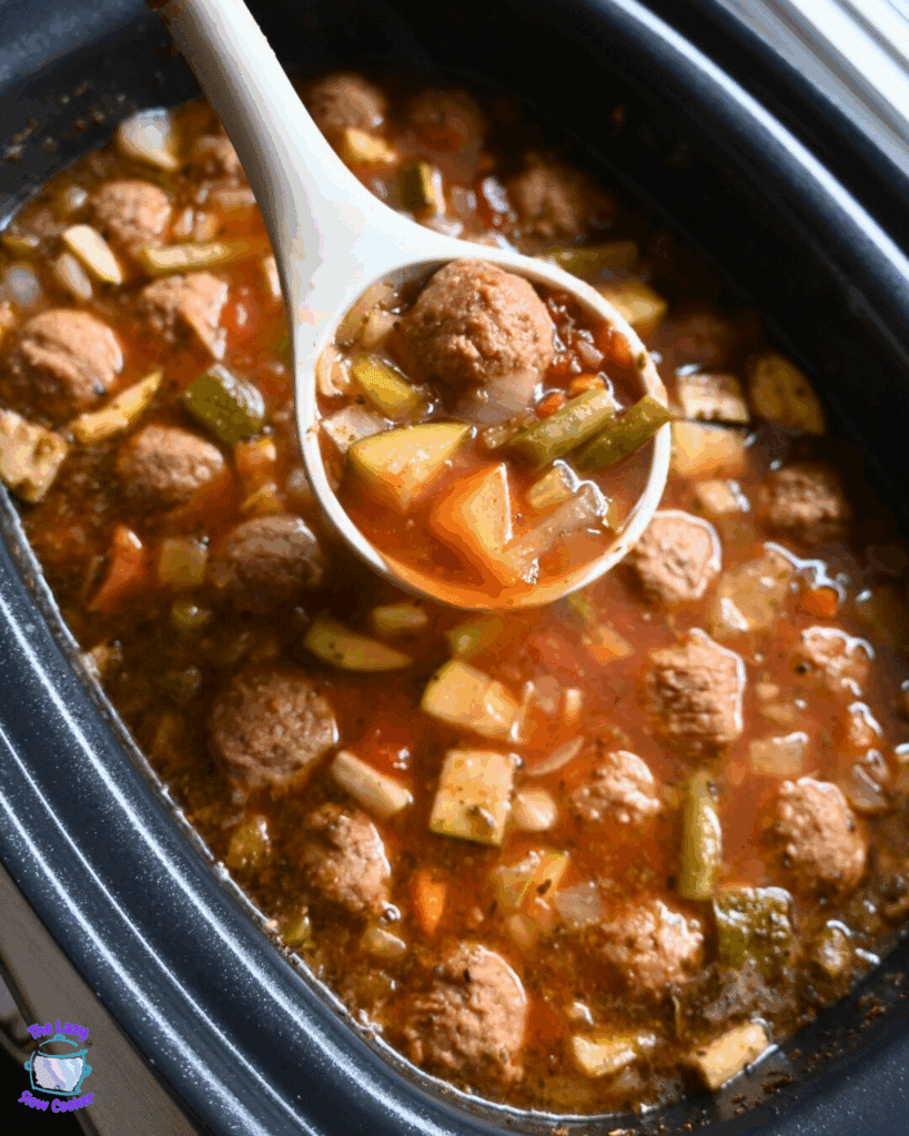A ladle full of meatball vegetable soup held over a crockpot full of the same