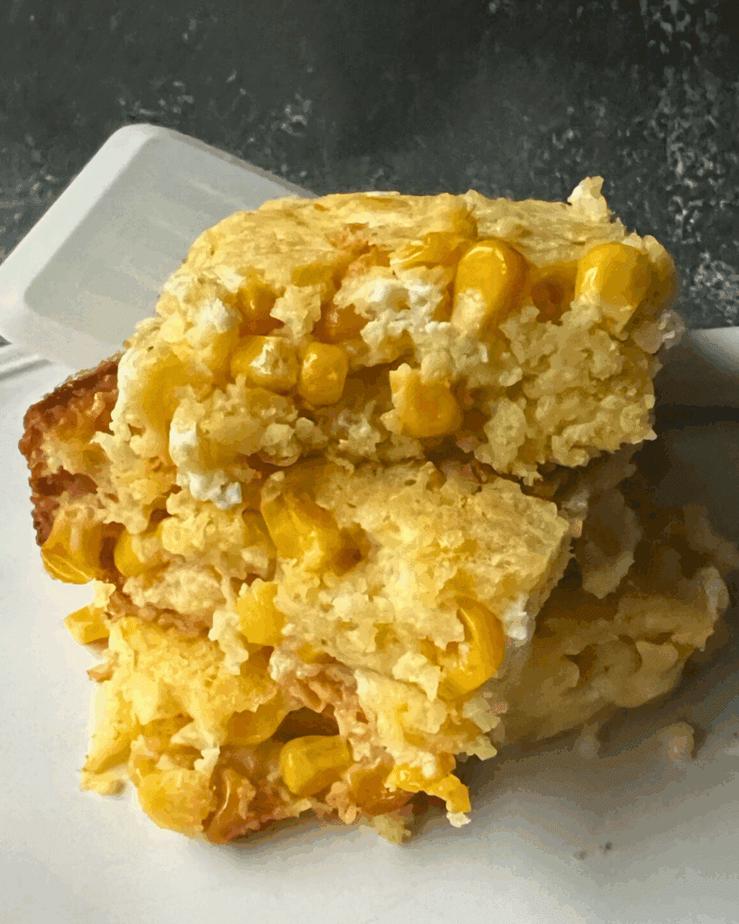 slow cooker corn spoonbread pieces stacked on a plate with a spatula in the background