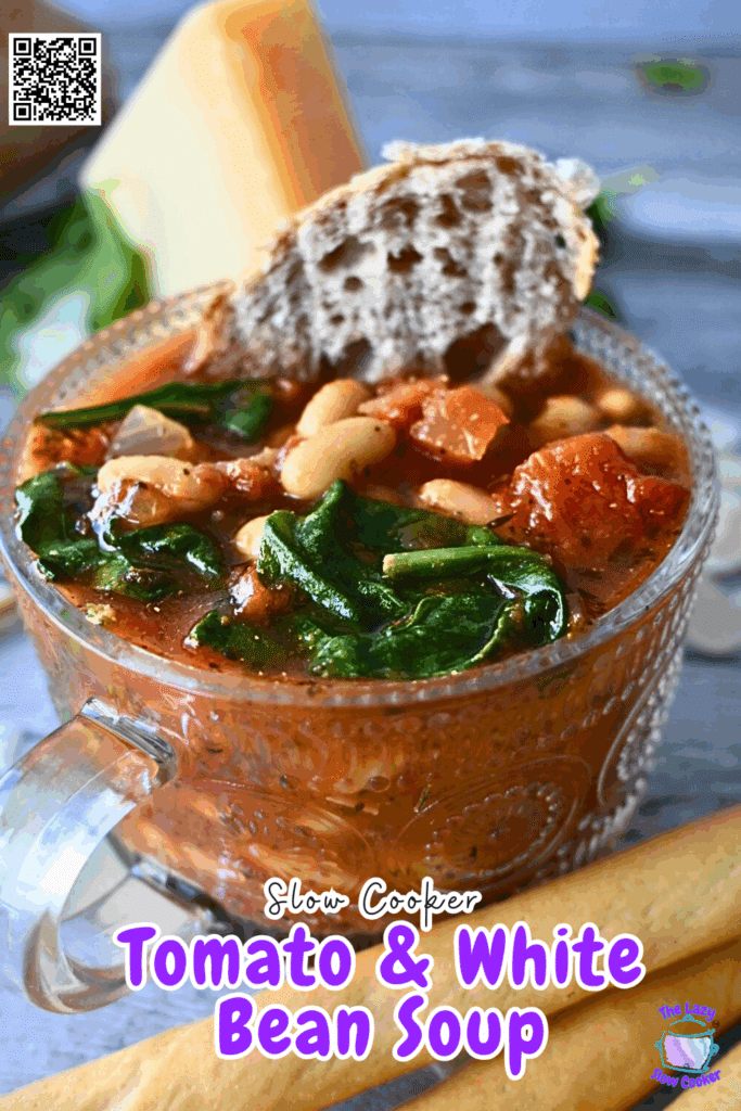 A bowl of slow cooked tomato and white bean soup with spinach, garnished with fresh basil. The bowl is on a wooden surface.