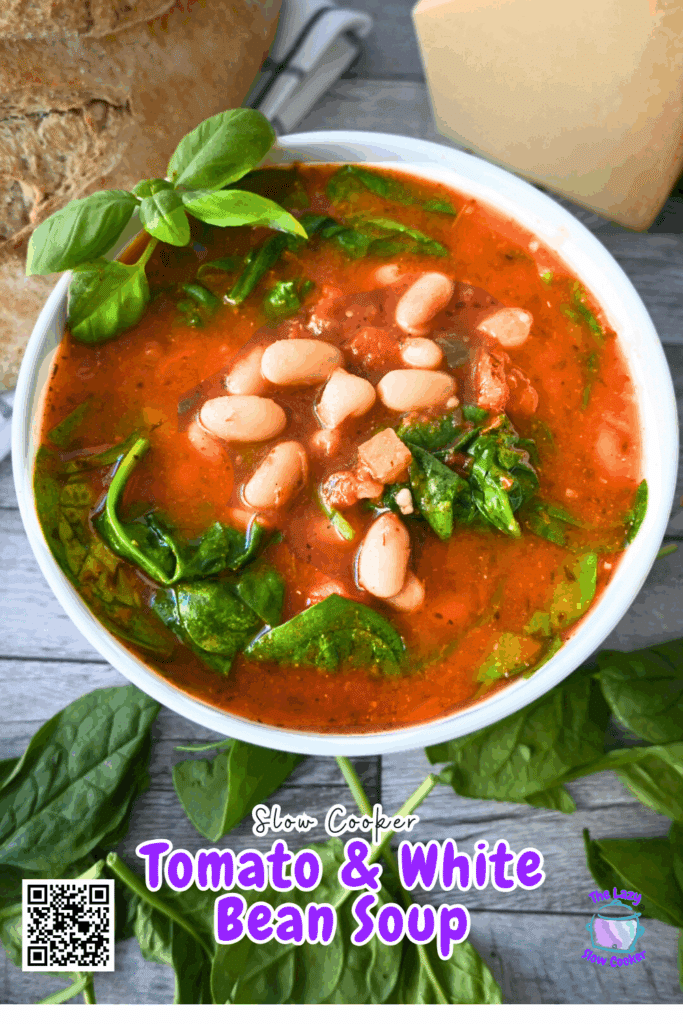 A bowl of tomato and white bean soup with spinach, garnished with fresh basil. The text reads Slow Cooker Tomato & White Bean Soup. A QR code and a logo are in the corners. The bowl is on a wooden surface.