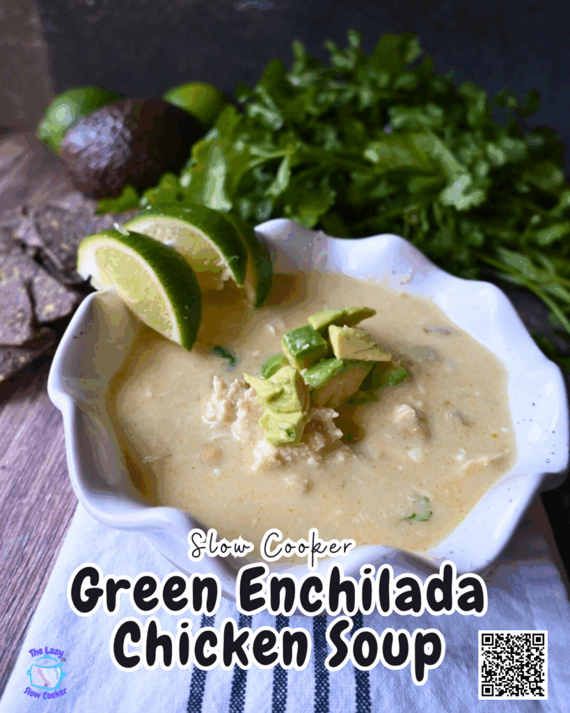A bowl of creamy green enchilada chicken soup topped with avocado and lime wedges sits on a white napkin, with fresh cilantro and an avocado in the background. Text on the image reads, Slow Cooker Green Enchilada Chicken Soup
