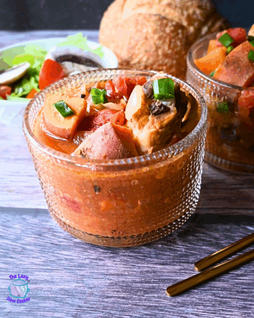 A glass bowl of soup with vegetables and meat.