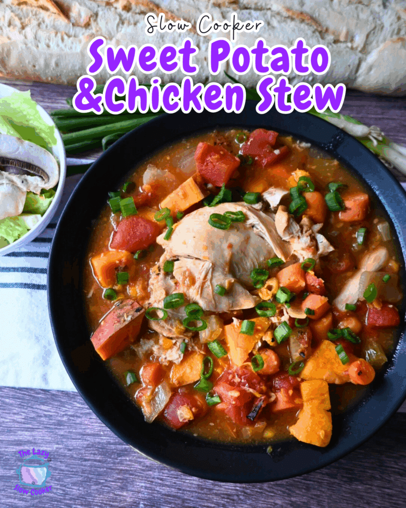 A bowl of chicken stew with sweet potatoes, tomatoes, and green onions, garnished with chopped green onions. A baguette, lettuce, mushrooms, and green onions are in the background on a wooden surface.