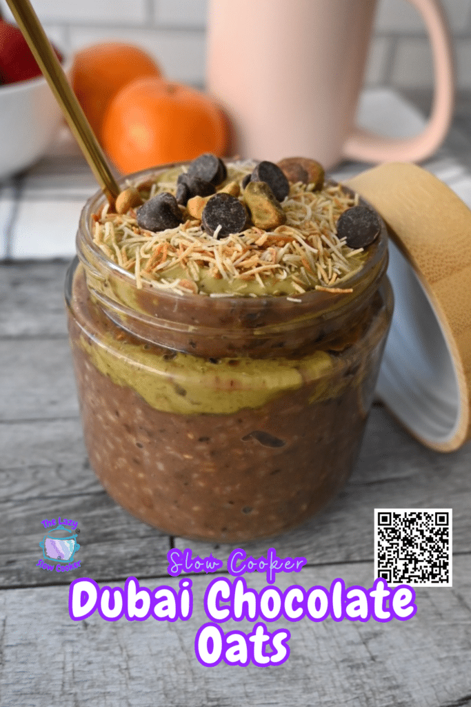 A jar with chocolate oats, pistachio butter, toasted kataifi and chocolate chips sits with a gold spoon. Text reads "Slow Cooker Dubai Chocolate Oats." Fruit and a QR code are in the background.